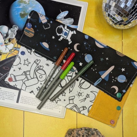 Coloriage lavable nomade sur le thème de l'espace plie en deux, feutres posés dessus