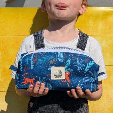 Enfant tenant dans ses mains la trousse à colorier aux motifs de singes oranges