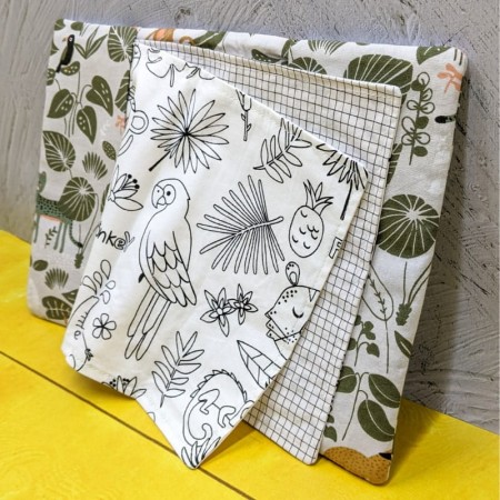 Cahier de coloriage lavable pampa posé verticalement et ouvert sur un coloriage aux motifs d'animaux de la jungle